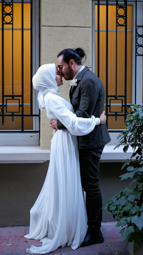 a bride and groom kiss outside in front of a house