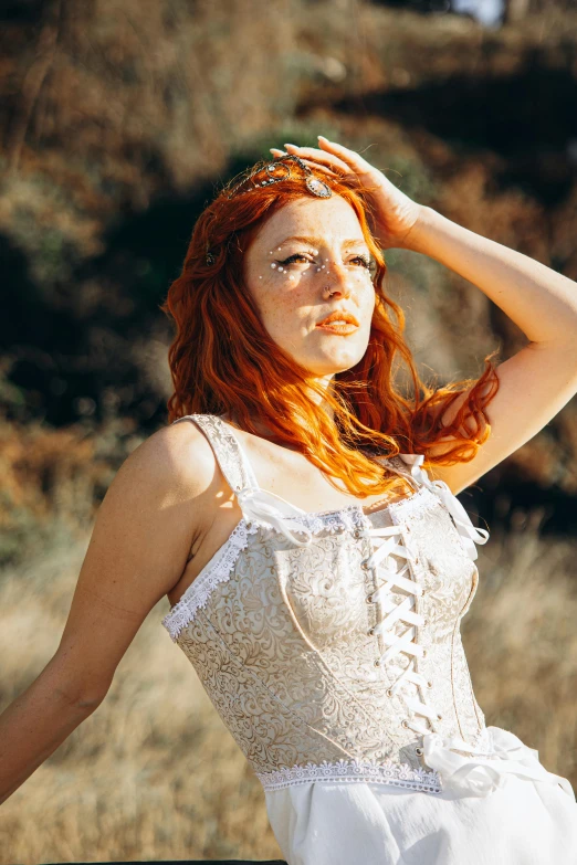 a red headed woman poses in a white dress