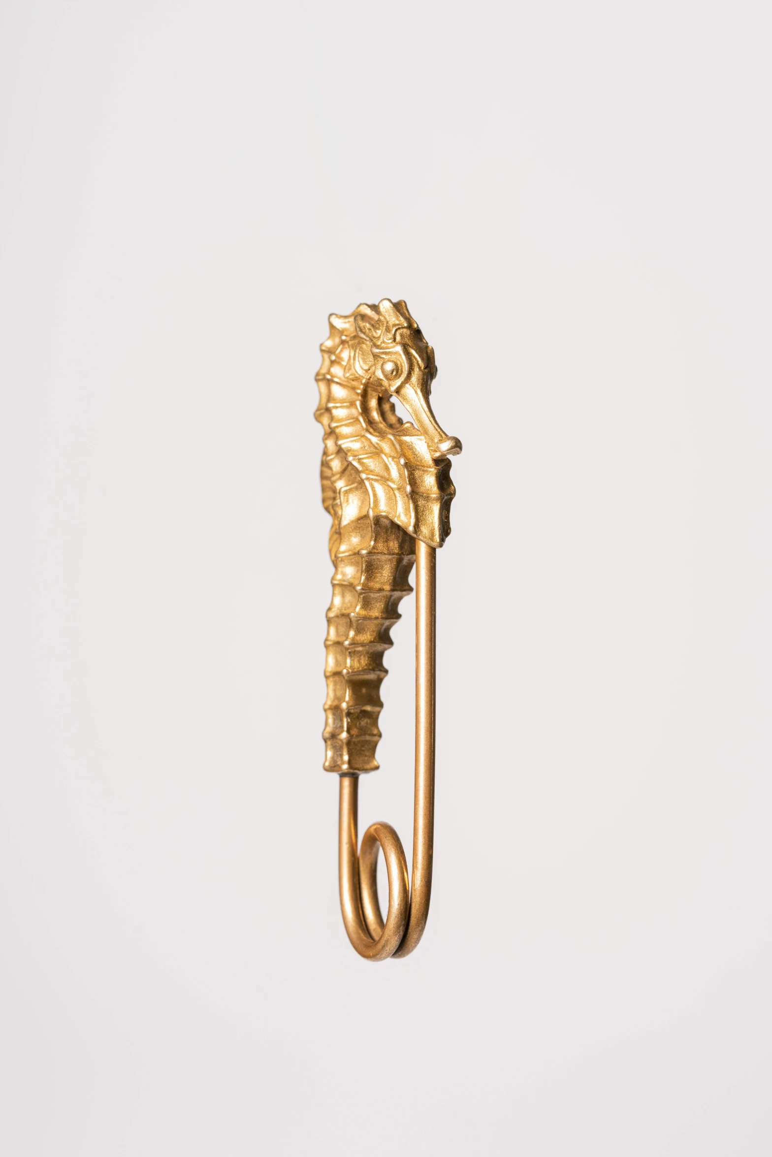 a gold sculpture of a seahorse hanging from a chain