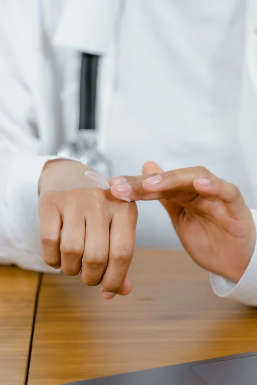 a man in a white coat sitting down holding a finger