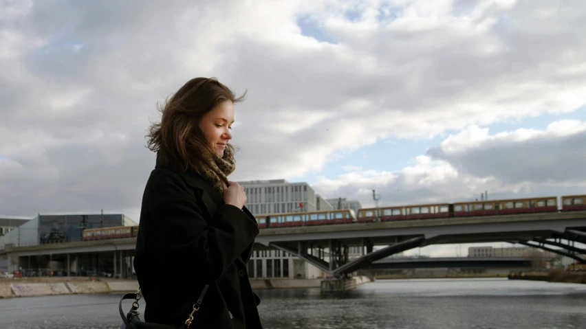 woman in black jacket standing on side walk near water