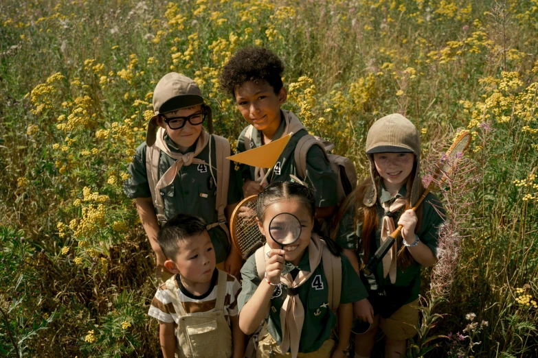 four young children with backpacks and goggles looking through magnifying glasses