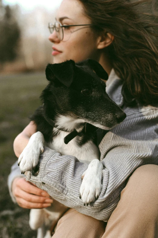 a woman is holding her dog in her arms