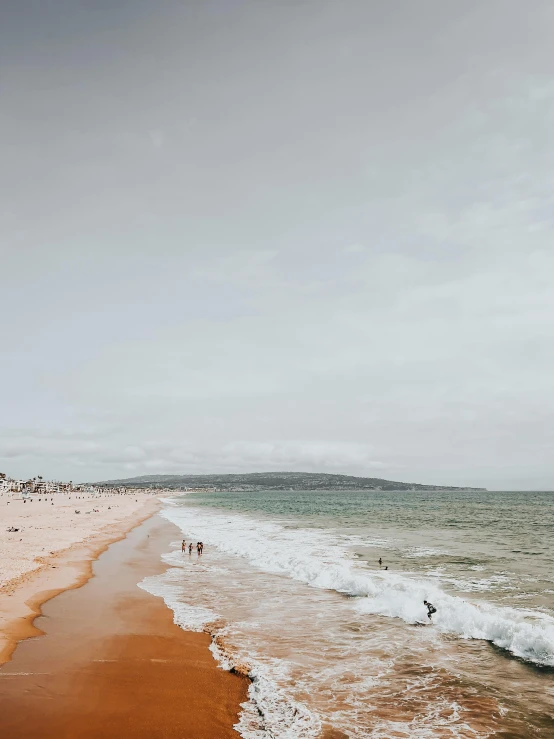 some people walking on a sandy beach by the water