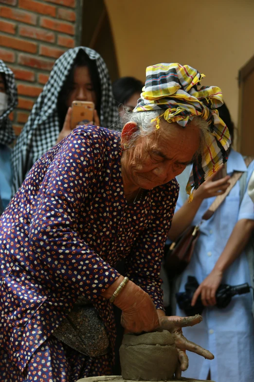 a woman is making soing with clay and a large stone wheel