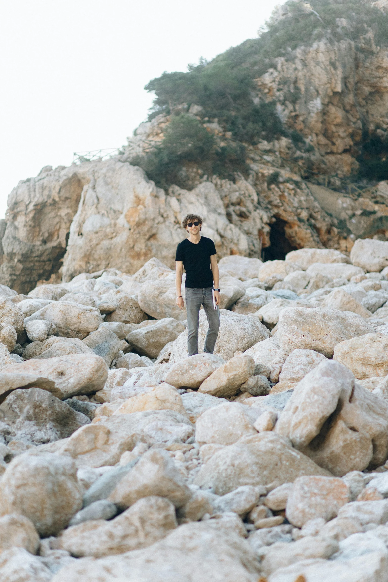 a man standing in the middle of rocks on a beach