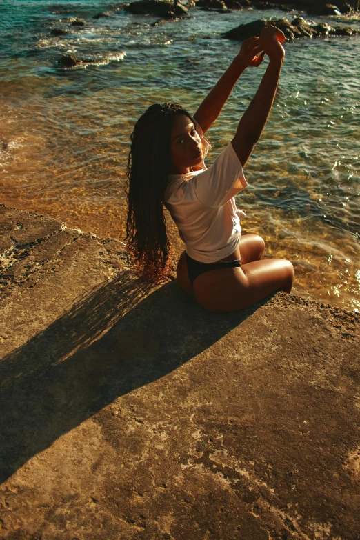 a woman sitting on the edge of a beach by a body of water