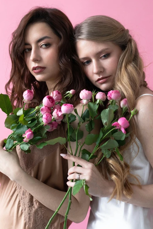 two women hold roses and a pink background