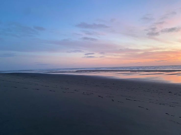 the sunset reflects in a body of water along the beach