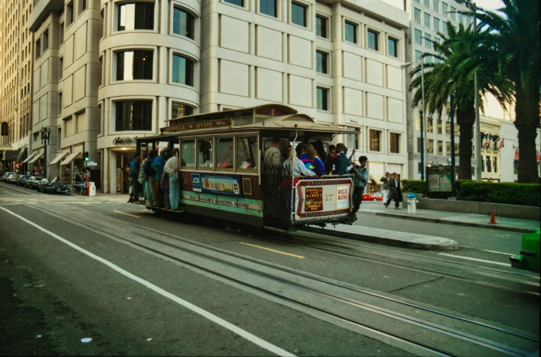 a trolley car full of people traveling down the road