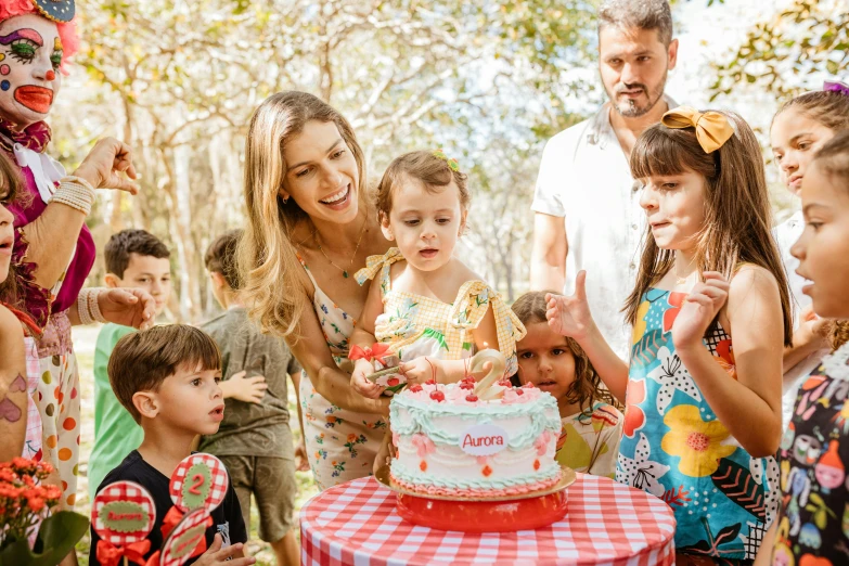 a woman and children gather around a birthday cake