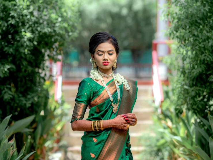 woman in green silk sari with gold accents standing outside