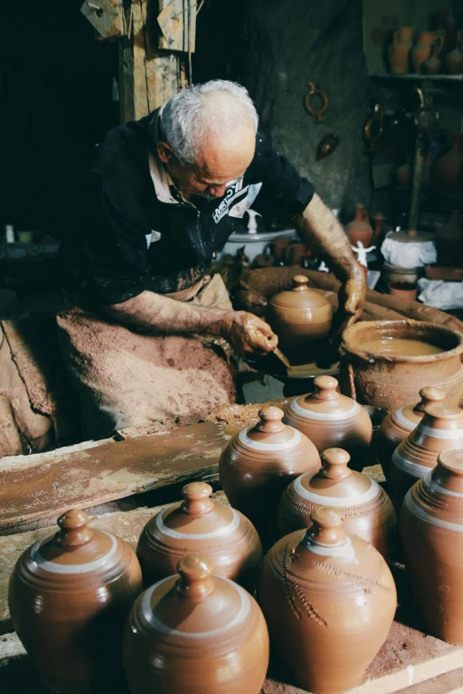 a man is decorating pottery in his workshop