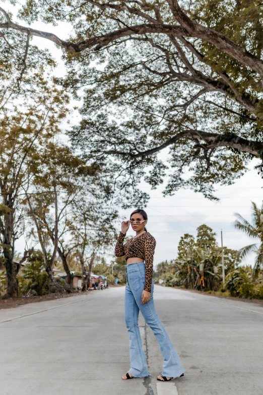 a woman standing on the road in front of trees