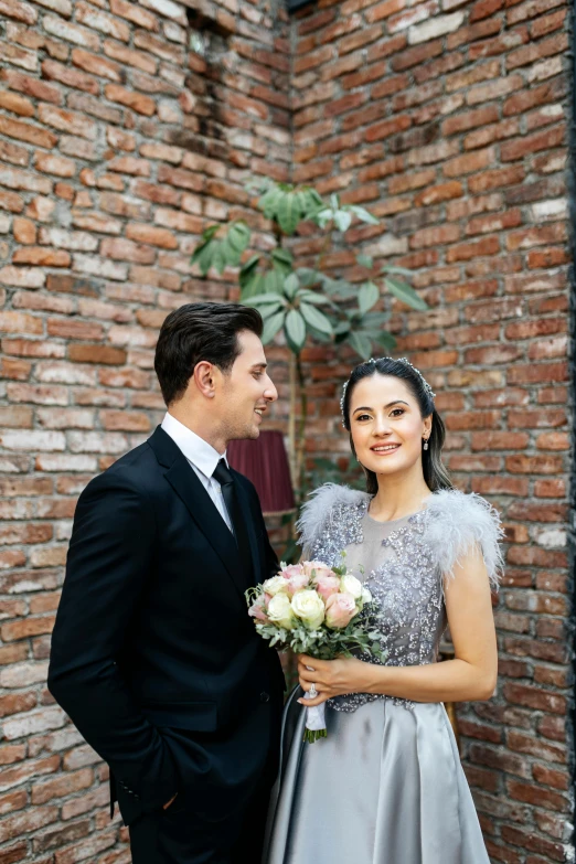 a man standing next to a woman in front of a brick wall