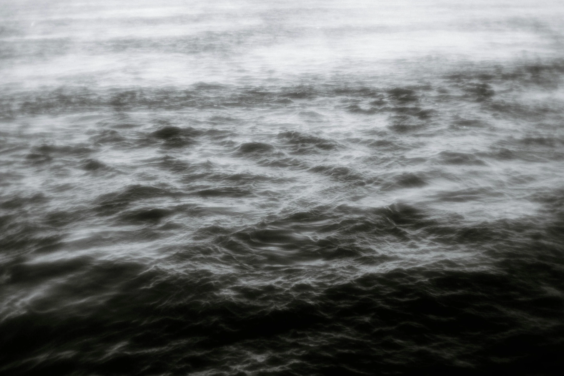 white ocean with small clouds on the horizon