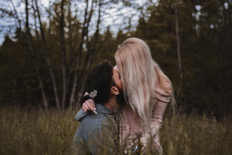 the blonde woman has her face close to the man's head