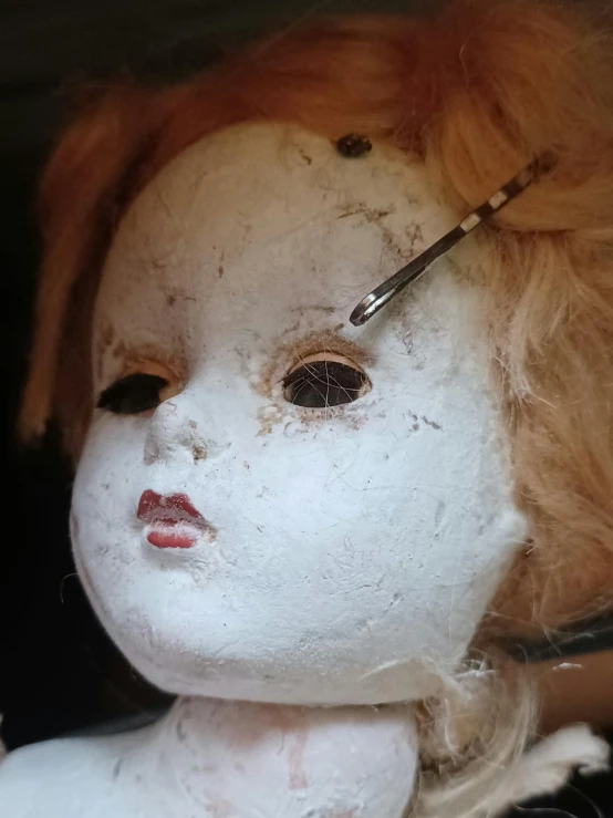 a white doll with red hair with one eye closed