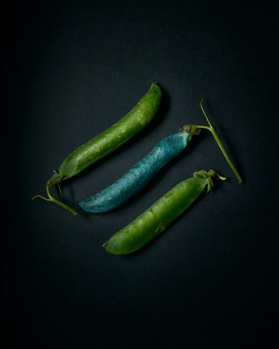 three pea pods on black background