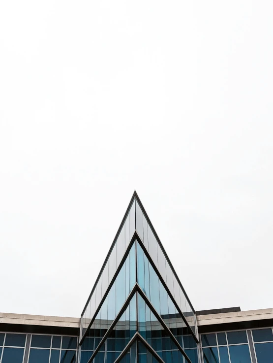 large triangular building with glass windows against a white sky