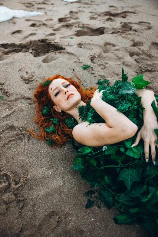 red haired woman lying in green dress on beach