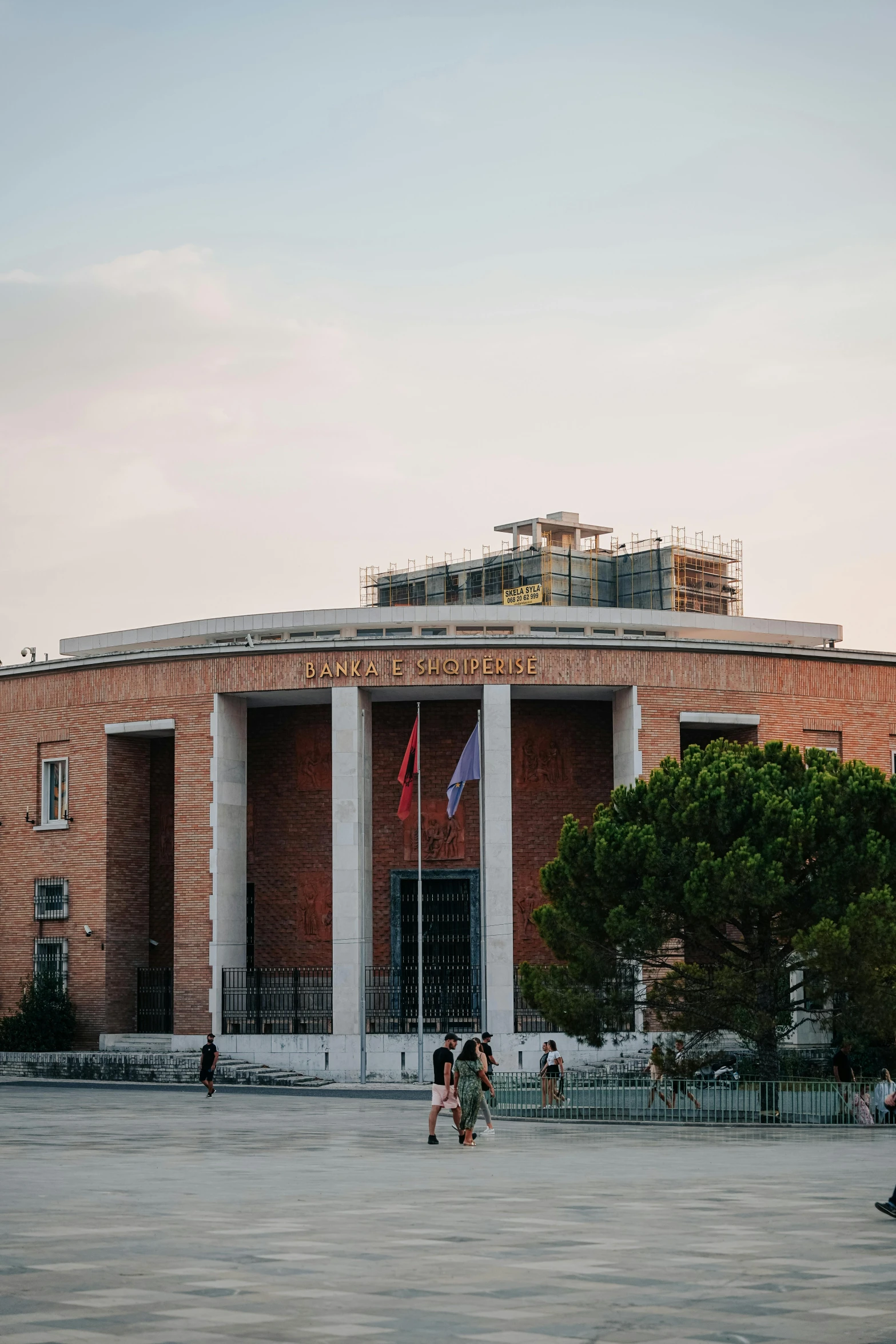 people are walking through an empty courtyard near a large building