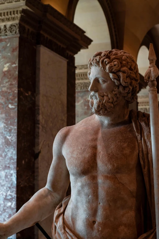 a statue of a man holding an arm, wearing a cape and a book