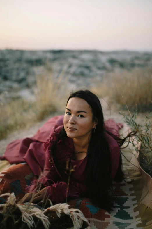 a woman is sitting on a blanket while staring ahead