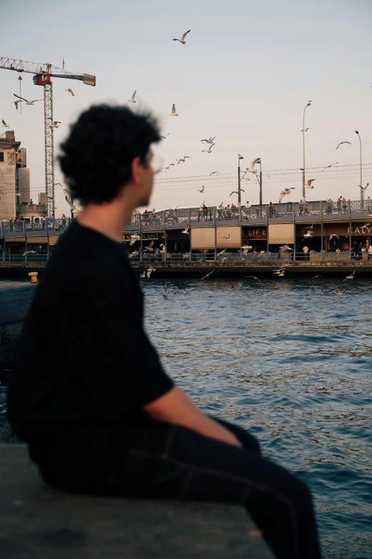 a man sitting on a ledge with his feet on the water