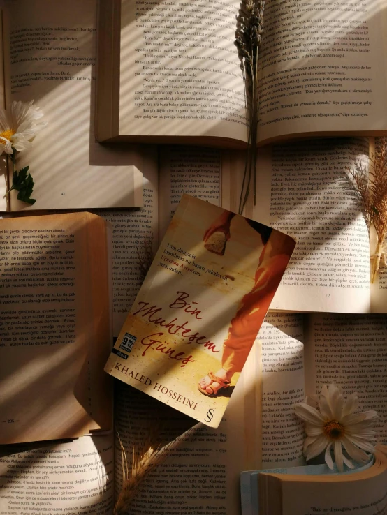 a stack of books covered in fake grass next to a flower