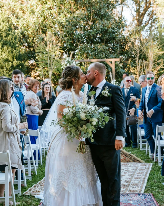 a newly married couple kissing under an arch in front of a wedding ceremony