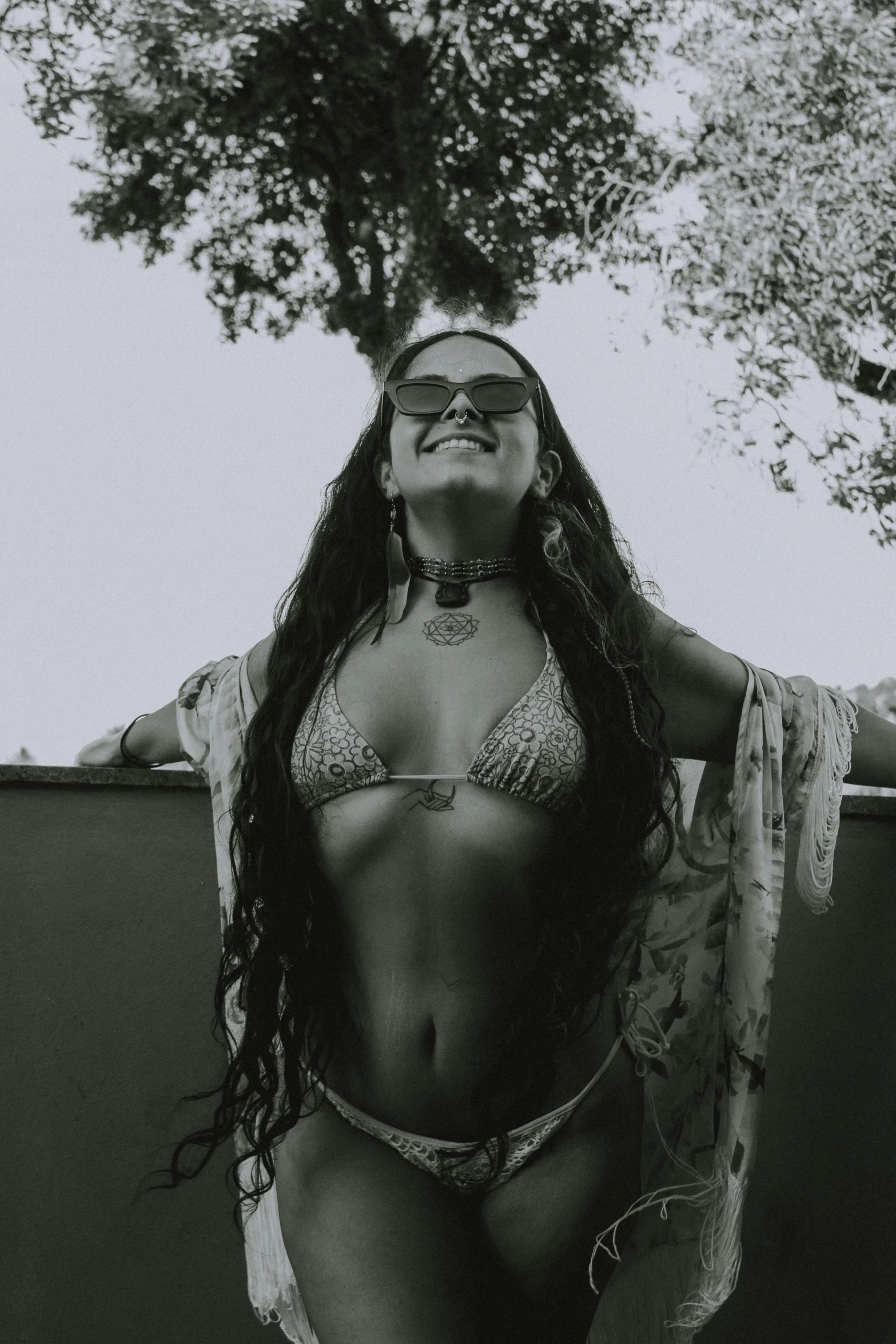 a woman is standing outside in a bikini and has her hands behind her back, wearing eyeglasses, on a boat