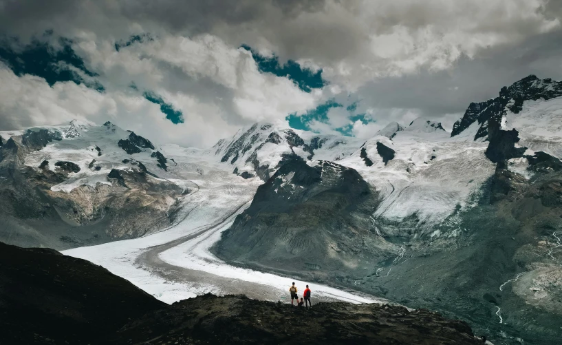 some mountains snow clouds and a person in red