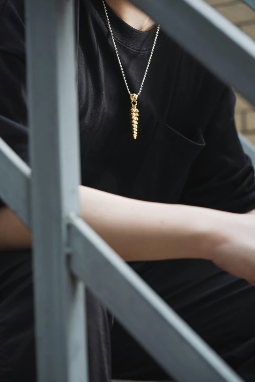 a man leaning against the fence while wearing a necklace with an elephant on it