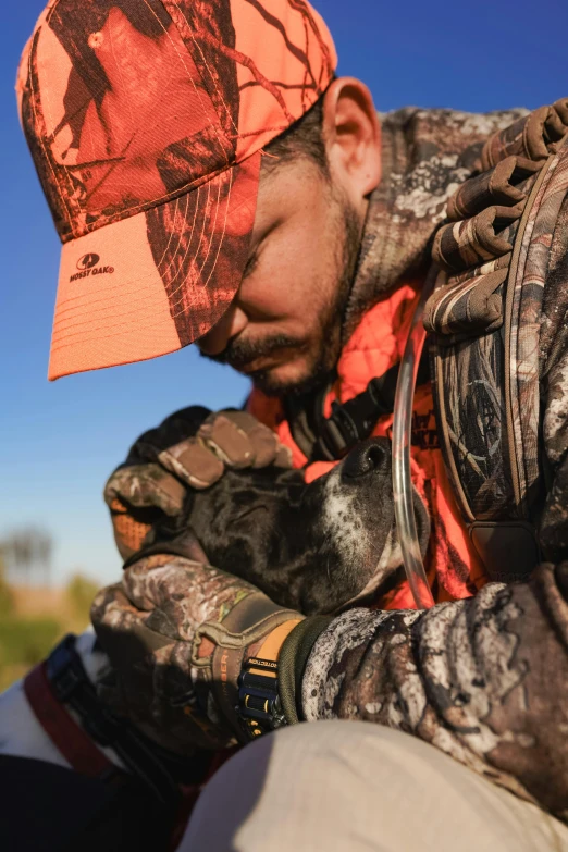 a man holding onto his glove while wearing an orange hat