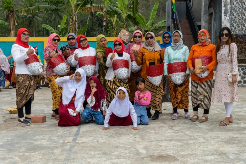 a large group of people stand together on a dirt surface