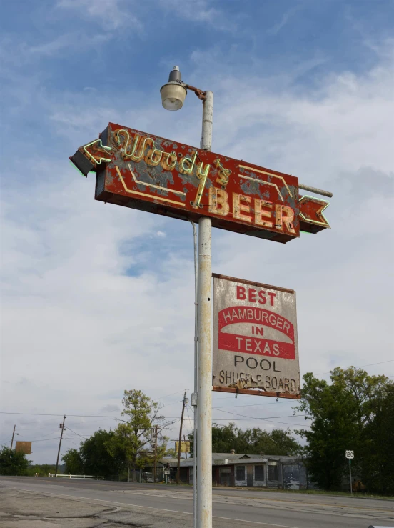 an old fashioned sign stands tall, with advertising nearby