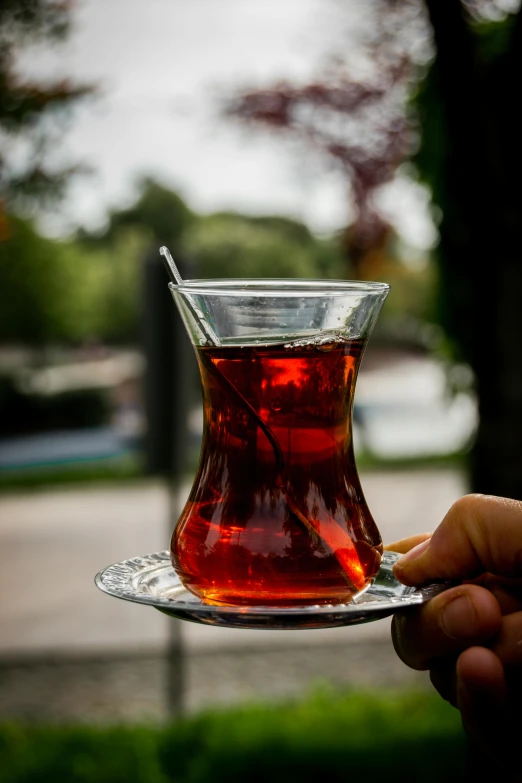 someone holding a glass cup that is filled with tea