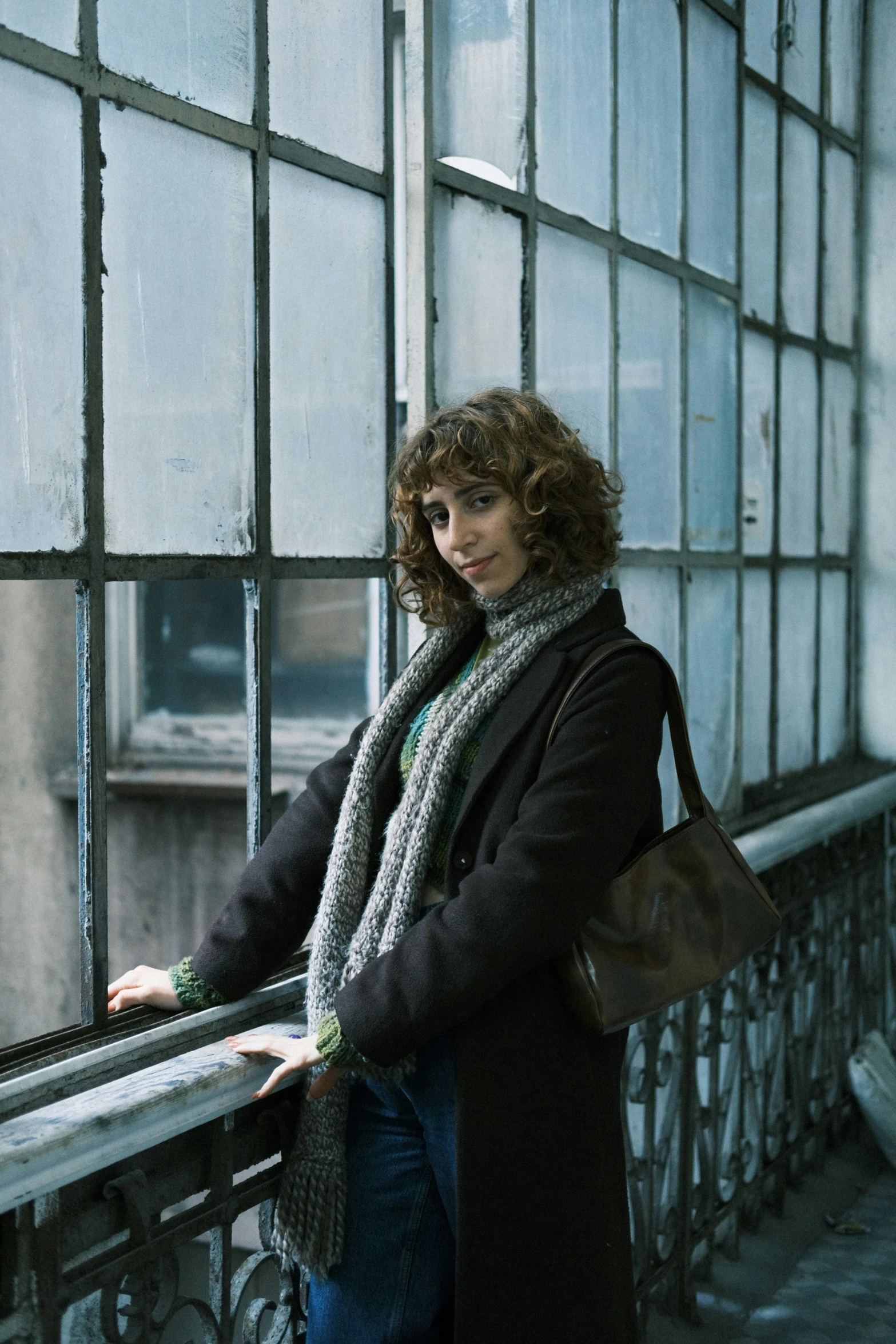 a woman leans against the railing of a glass building