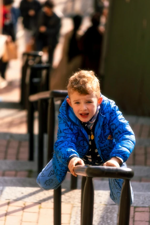 a small boy sitting on a railing