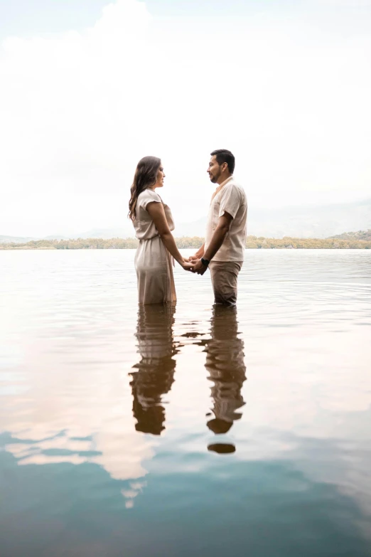 a man and woman standing in the water holding hands