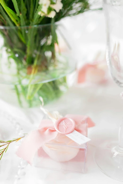 a table set with white flowers, pink and purple napkins and candles and wine glass