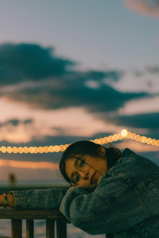 a woman leaning on a railing at dusk