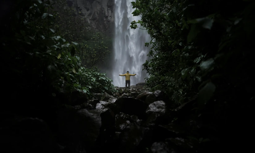 the man is in front of a large waterfall