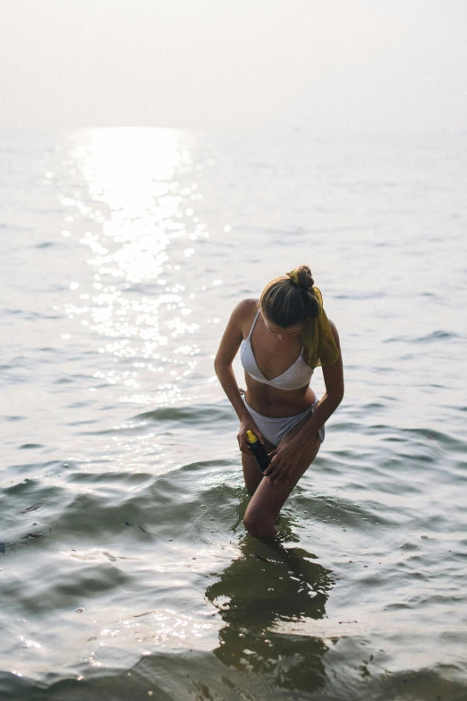 a woman is kneeling in the water next to the beach