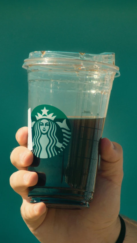 someone holding a starbucks cup with their thumb