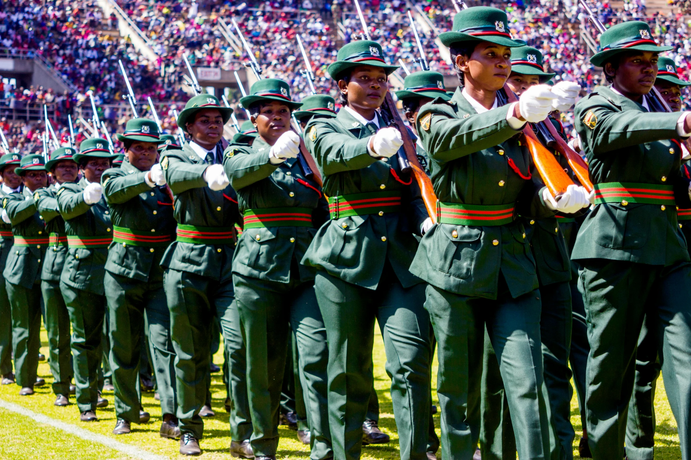 a group of uniformed people stand and wave in unison