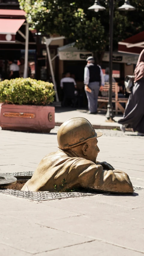 a statue of an older man sitting on the sidewalk