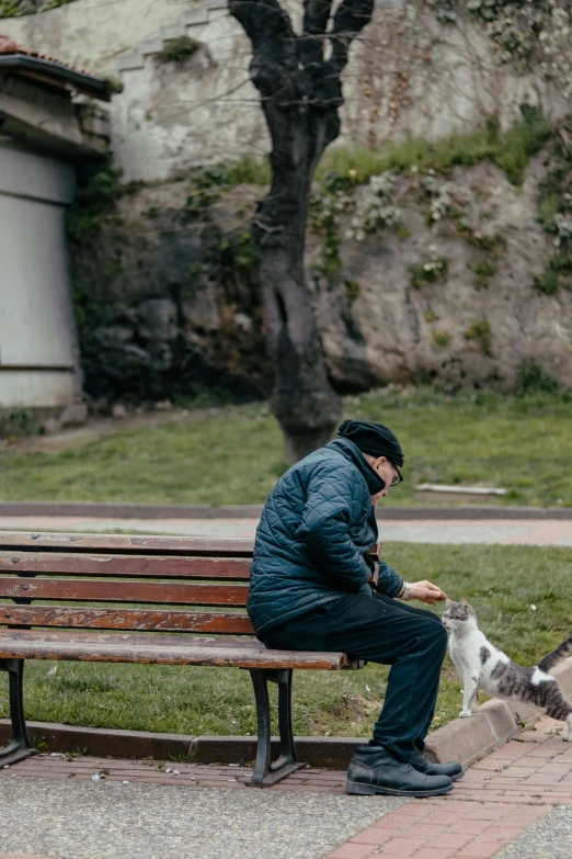 a man sits on a bench with his dog and holds soing