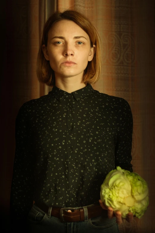 a woman is holding up a big head of cabbage